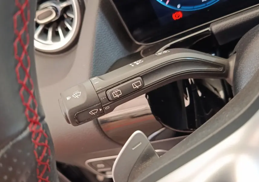 Gros plan sur la commande d’essuie-glace à gauche du volant cuir noir avec surpiqûres rouges du Mercedes GLA 250 e AMG LINE.