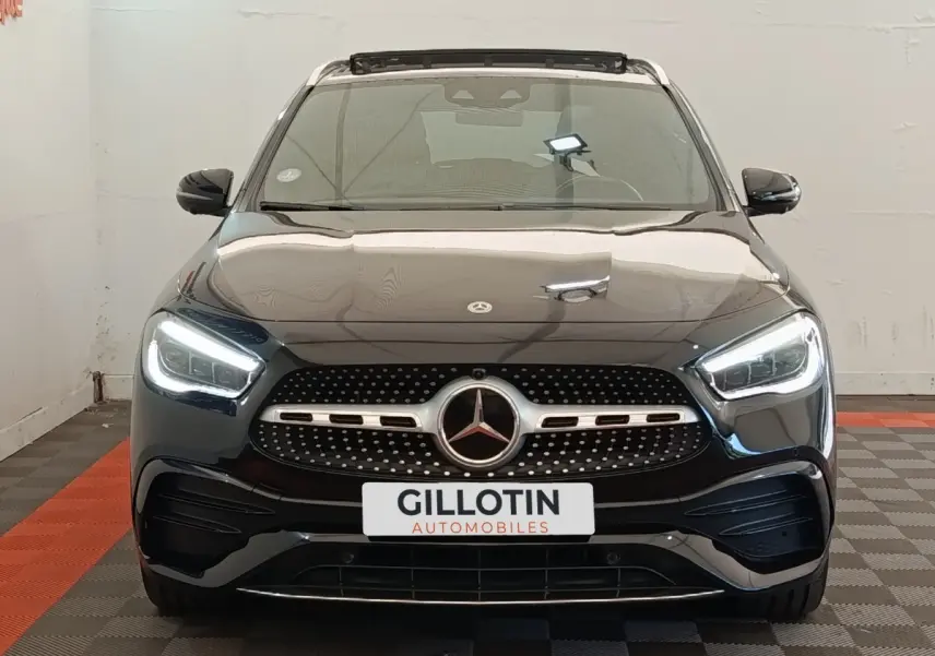 Vue avant d'un Mercedes GLA 250 e AMG Line noir avec phares LED allumés dans un showroom.