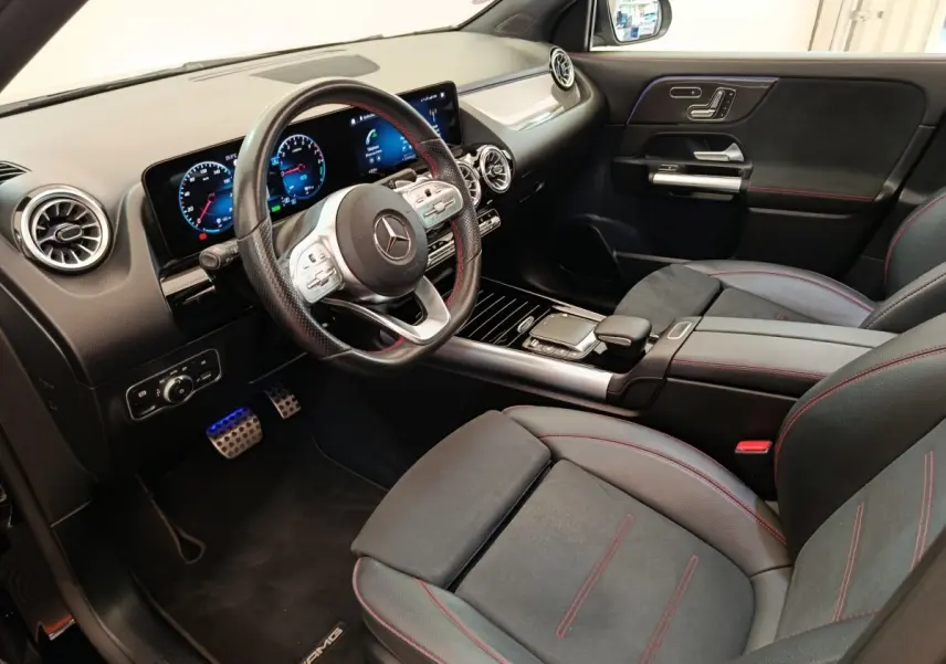 Vue intérieure côté conducteur du Mercedes GLA 250 e AMG Line 2021, sièges noirs avec surpiqûres rouges et tableau de bord digital.