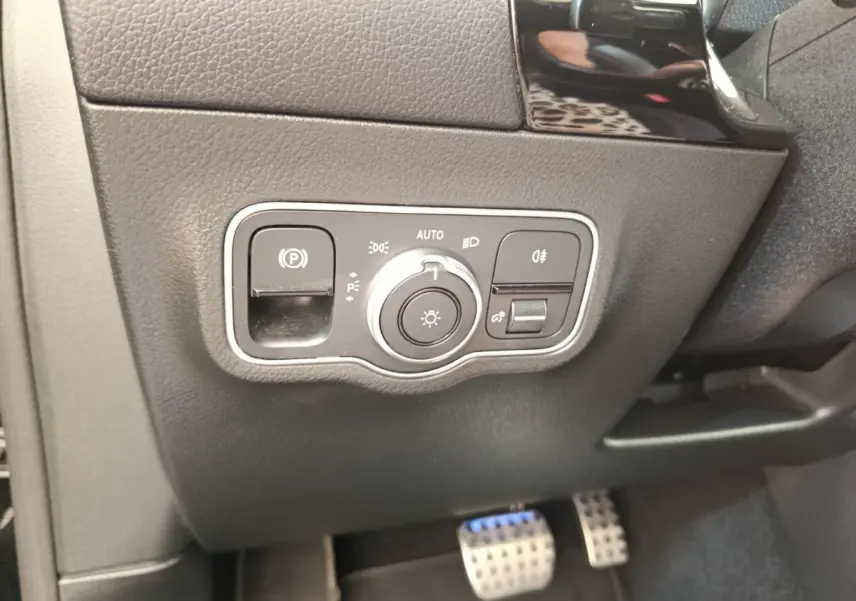 Gros plan sur la commande des feux et frein de stationnement, côté gauche intérieur d’une Mercedes GLA 250 e AMG Line noir 2021.