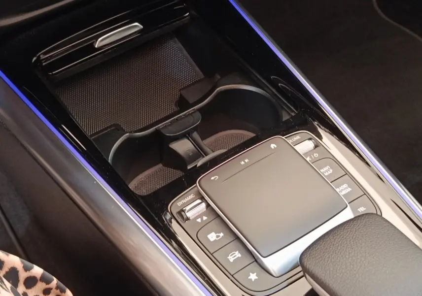 Vue rapprochée de la console centrale noire du Mercedes GLA 250 e AMG Line avec pavé tactile et porte-gobelets.