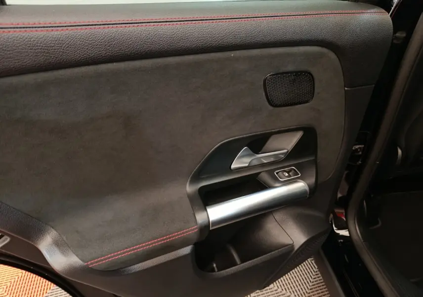 Gros plan sur la porte arrière droite noire du Mercedes GLA 250 e AMG Line 2021 avec surpiqûres rouges et poignée alu.