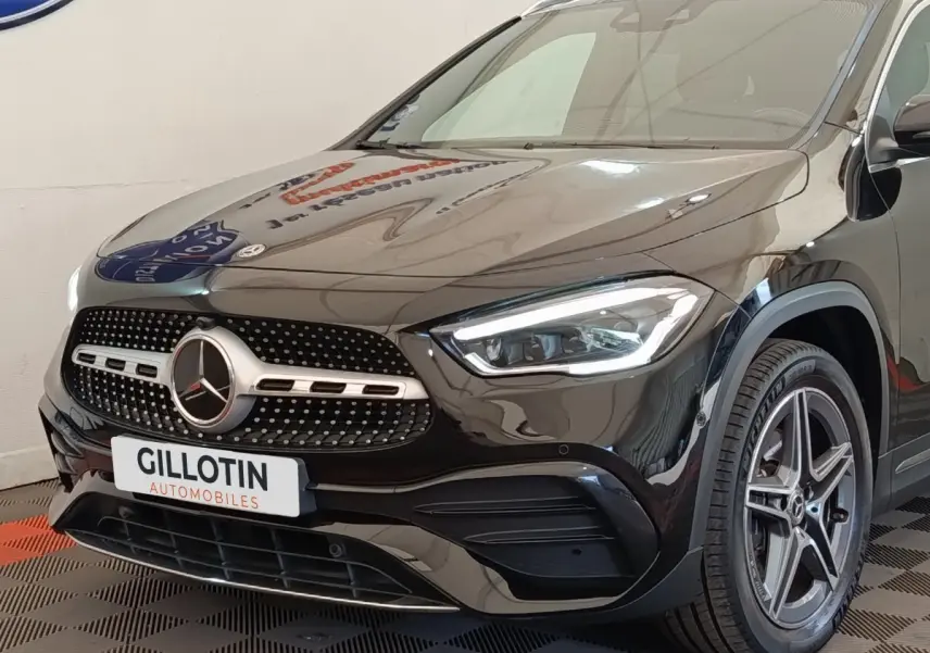Vue 3/4 avant droite d'une Mercedes GLA 250 e AMG Line noire avec calandre étoile et phares LED allumés.