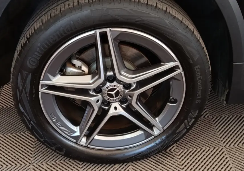 Gros plan sur la roue avant droite avec jante AMG gris métallisé du Mercedes GLA 250 e noir hybride rechargeable.