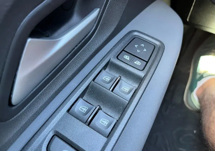 Gros plan sur les commandes des vitres électriques côté conducteur du Dacia Jogger gris schiste 2025, version hybride.