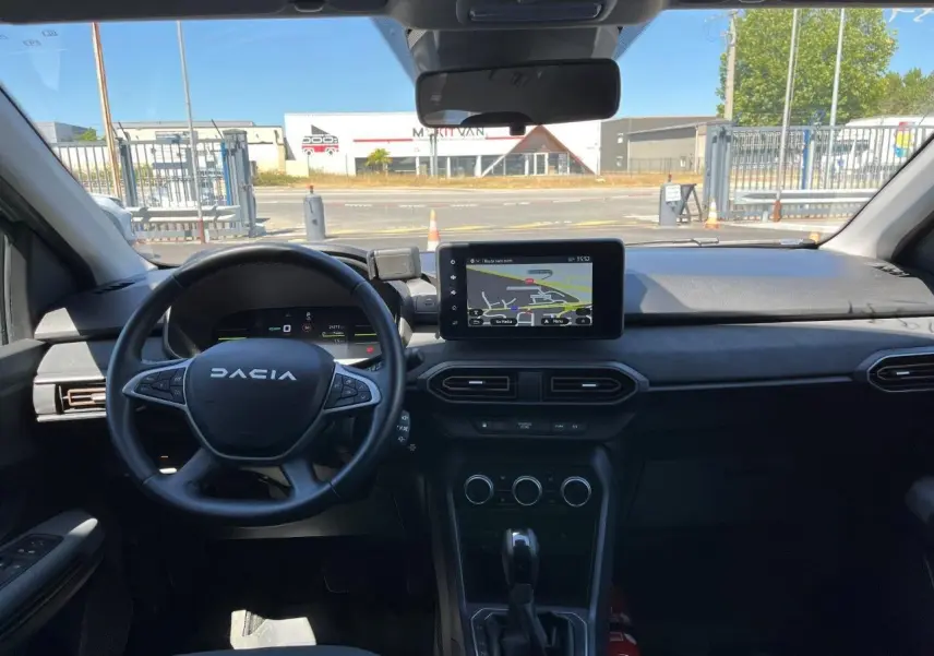 Vue intérieure frontale du tableau de bord du Dacia Jogger 2025 avec écran tactile GPS et volant multifonction noir.