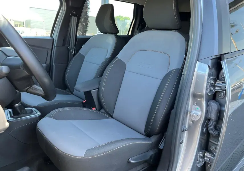 Vue intérieure côté conducteur du Dacia Jogger gris schiste 2025, montrant les sièges avant bi-matière avec surpiqûres contrastantes.