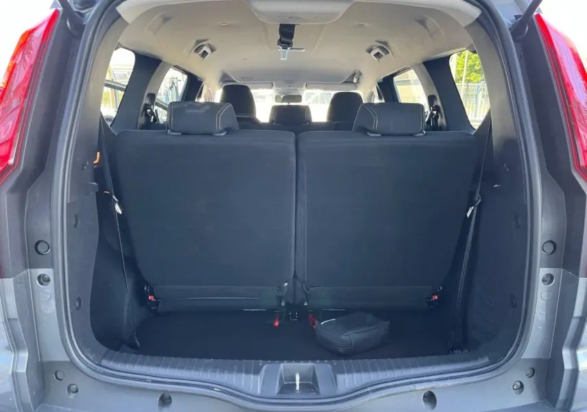 Vue arrière du coffre ouvert du Dacia Jogger gris schiste 2025, montrant les sièges arrière relevés et l’habitacle lumineux.