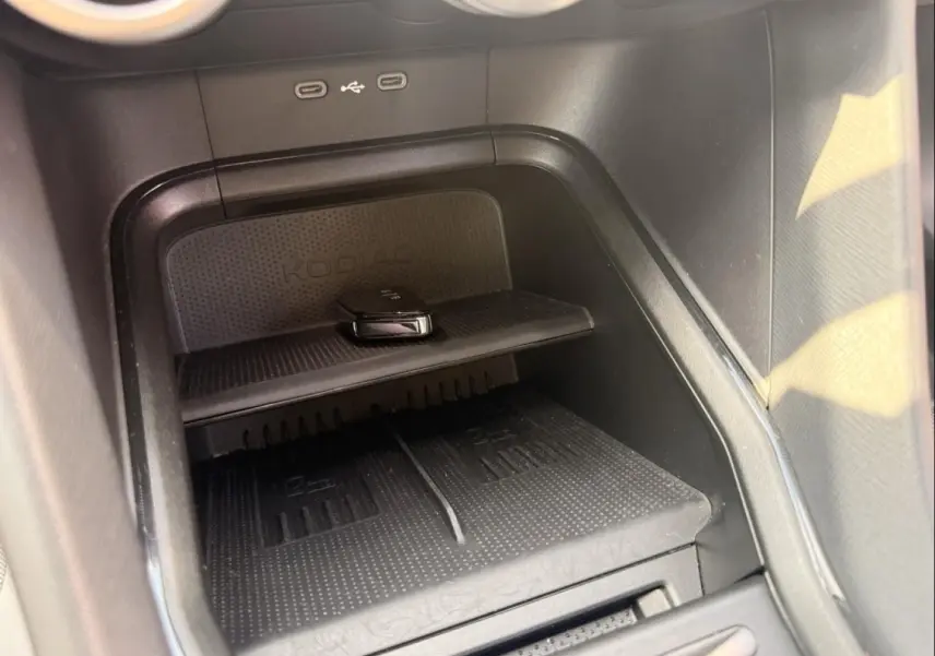Détail de la console centrale noire du Skoda Kodiaq 2024 montrant un espace de rangement avec chargeur sans fil et ports USB.