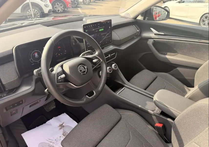 Vue intérieure côté conducteur du Skoda Kodiaq 2024 noir, montrant le volant, tableau de bord numérique et écran central tactile.