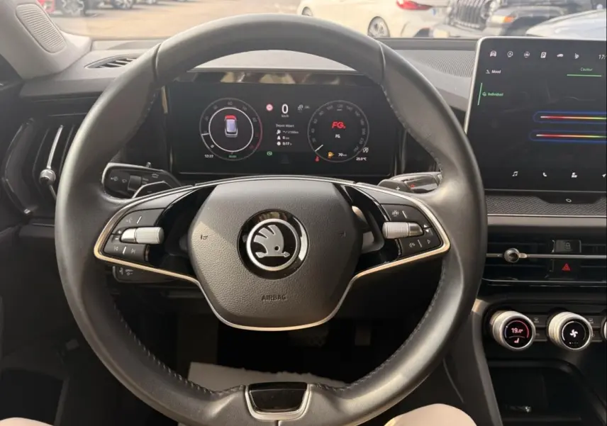 Vue intérieure centrée sur le volant noir du Skoda Kodiaq 2024 avec tableau de bord numérique et écran tactile.