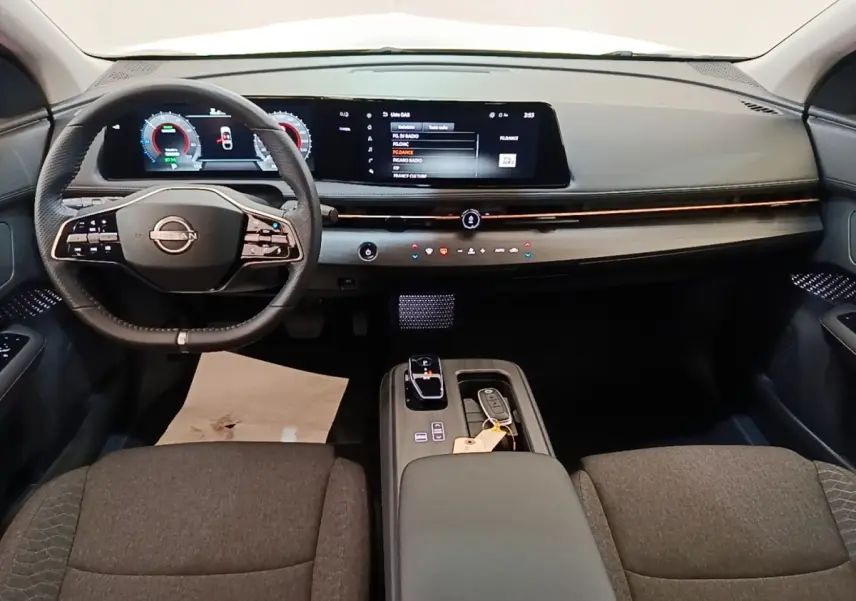 Vue intérieure avant du Nissan Ariya 63kWh noir, avec tableau de bord numérique et volant multifonctions cuir.