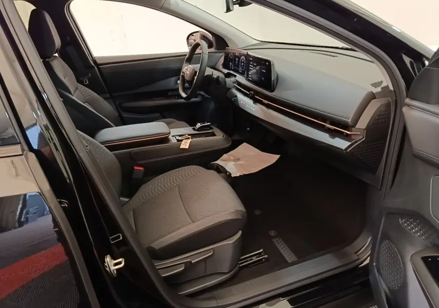 Vue intérieure côté conducteur du Nissan Ariya noir 2026, mettant en valeur le tableau de bord moderne et le volant cuir multifonctions.