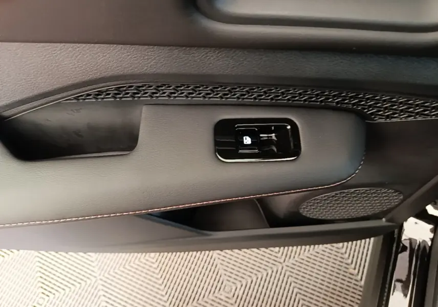 Gros plan sur la porte avant droite noire du Nissan Ariya 63kWh avec bouton de verrouillage et haut-parleur intégré.