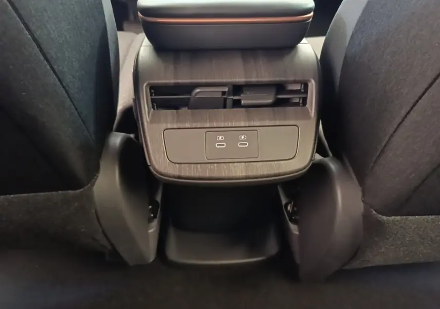 Vue rapprochée de la console arrière du Nissan Ariya noir avec prises USB-C et sortie d'air pour les passagers arrière.