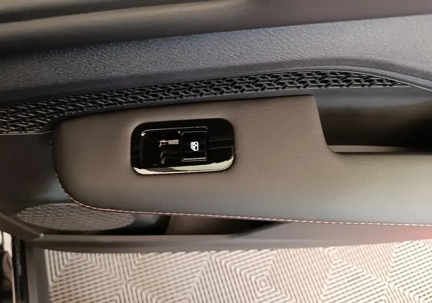 Détail de la commande de lève-vitre sur la porte intérieure côté conducteur du Nissan Ariya noir 2026.