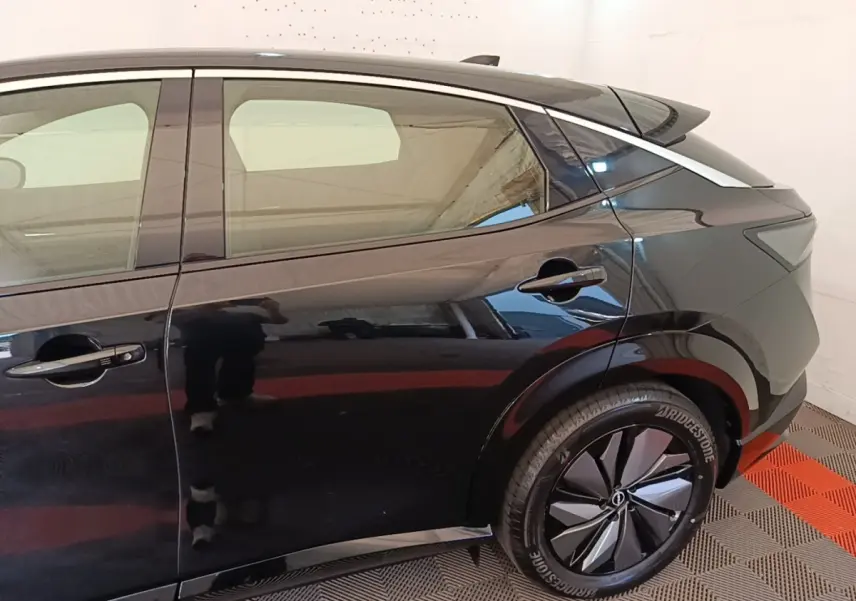 Vue latérale côté droit du Nissan Ariya noir 63kWh 218ch Engage, mettant en valeur la roue arrière et la ligne de toit dynamique.