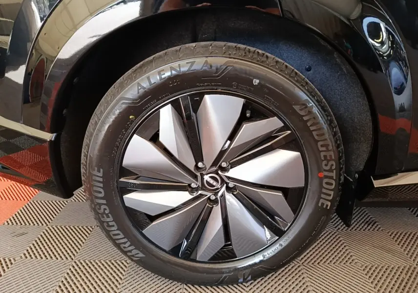 Gros plan sur la roue avant droite noire d’un Nissan Ariya 63kWh 218ch Engage avec jante alu bicolore.