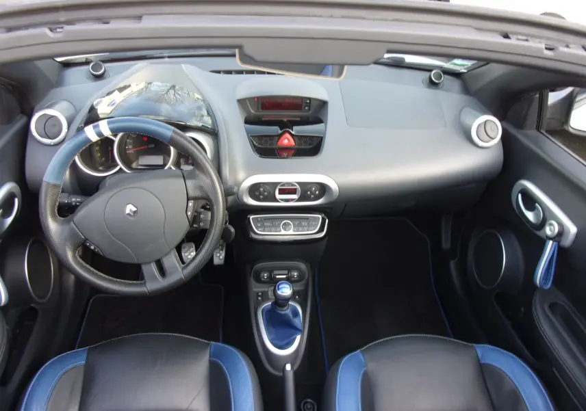 Vue intérieure du tableau de bord et volant de la Renault Wind 1.6 16V 133 Gordini avec sièges cuir noir et bleu.