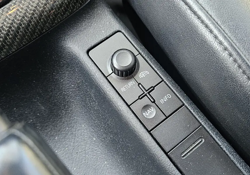 Gros plan sur la console centrale noire de l'Audi RS4 Avant B5, mettant en valeur les boutons de navigation et retour.
