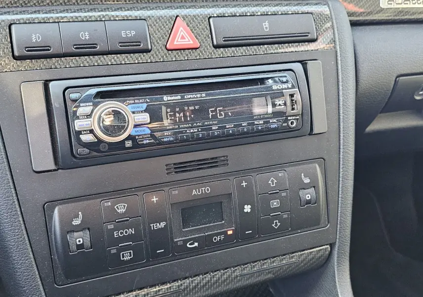 Gros plan sur la console centrale noire de l'Audi RS4 Avant B5, montrant autoradio Sony et commandes de climatisation.