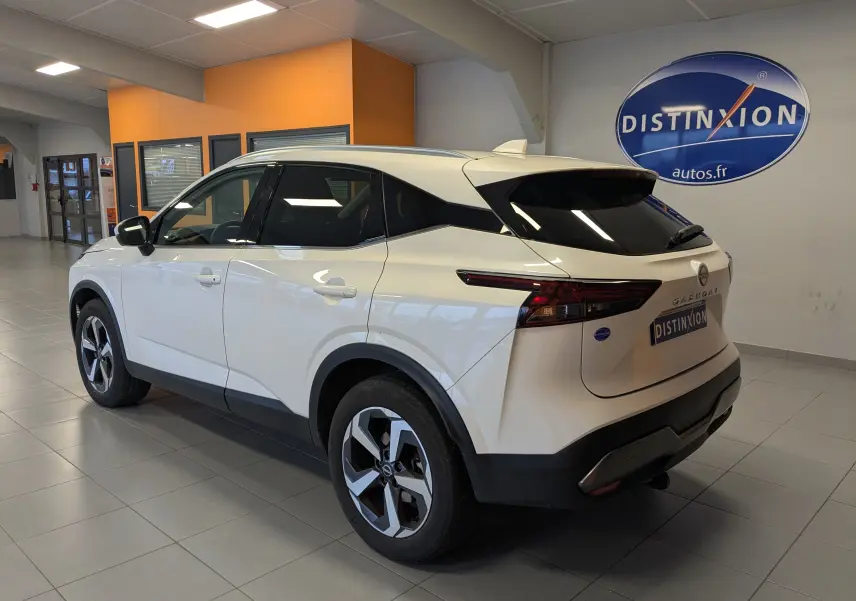 Vue 3/4 arrière droite du Nissan Qashqai blanc 2024 avec jantes bi-ton et toit noir en showroom intérieur.