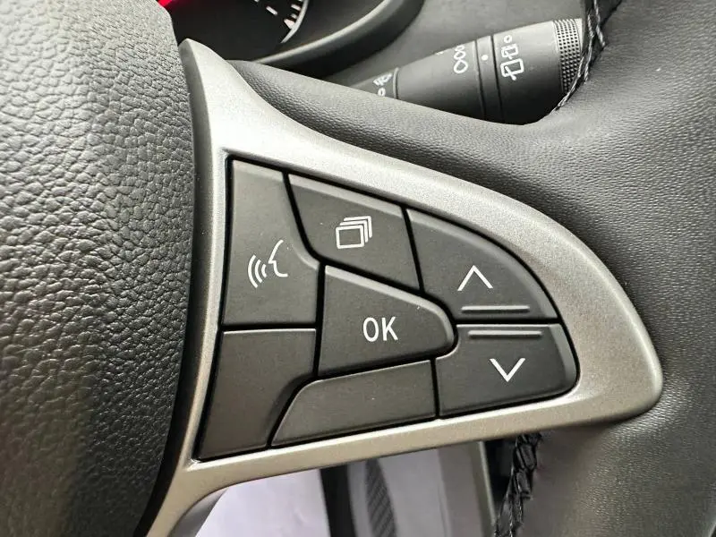 Gros plan sur les commandes multifonctions du volant du Dacia Jogger 2024, finition Extreme+, boutons noirs sur cadre argenté.