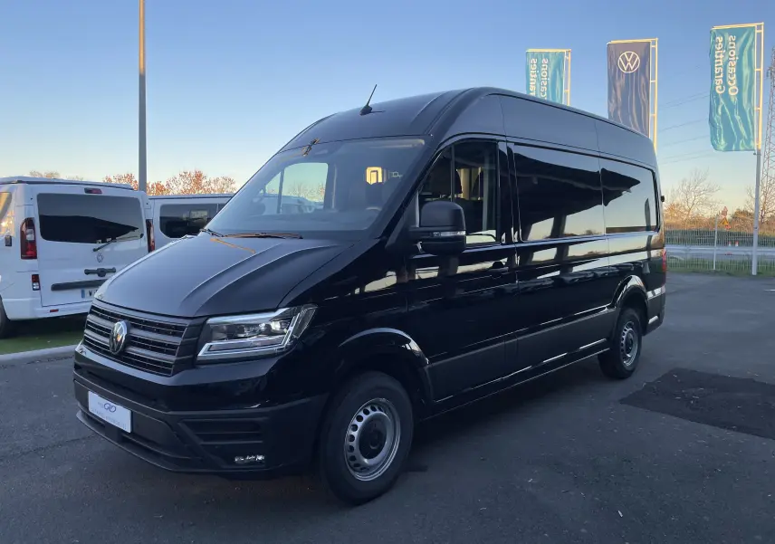 Volkswagen Crafter Van noir intense vu en 3/4 avant droit, avec phares LED et vitres teintées sur parking extérieur.