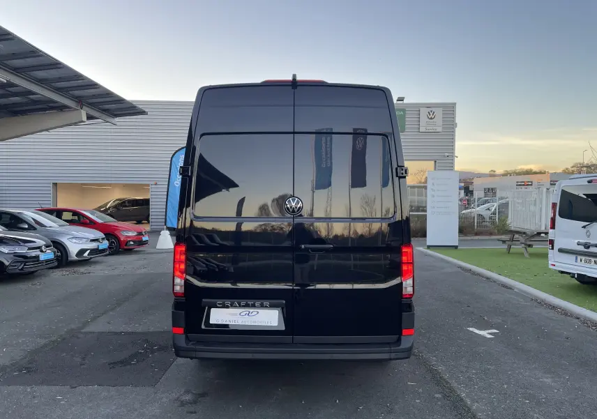 Vue arrière d'un Volkswagen Crafter Van noir intense 2025, avec portes battantes fermées et logo VW visible.