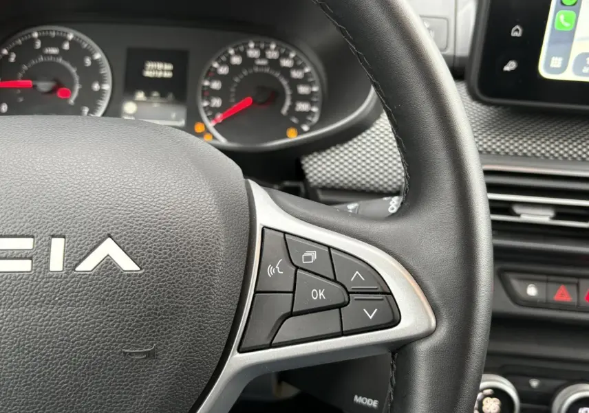 Vue rapprochée du volant côté droit du Dacia Jogger 2025, avec commandes multifonctions et tableau de bord en arrière-plan.