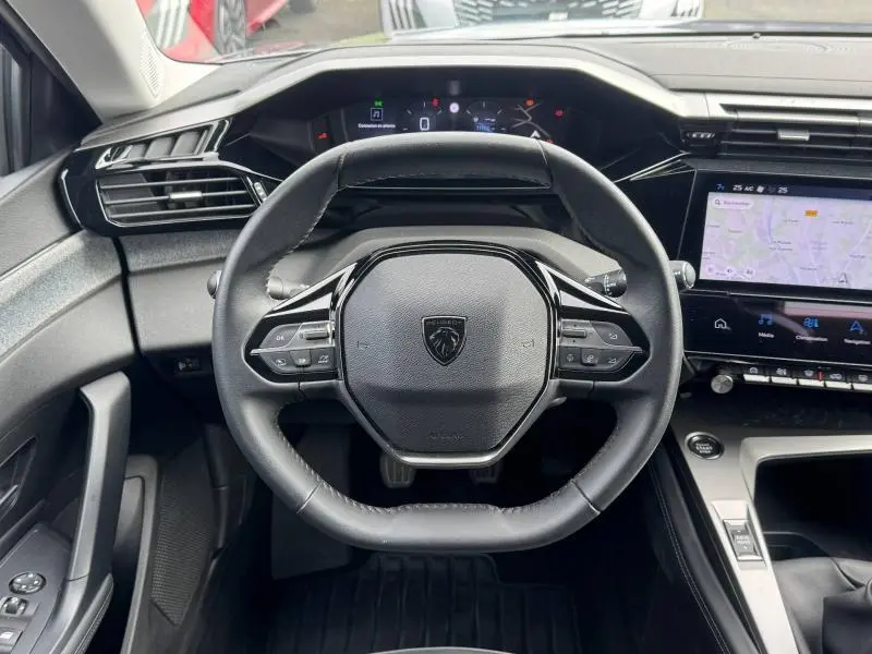 Vue intérieure centrée sur le volant compact de la Peugeot 308 2024 avec tableau de bord numérique et écran tactile.