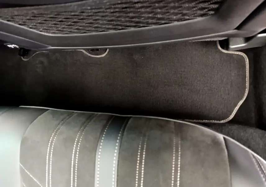 Vue rapprochée du tapis de sol noir et de la partie inférieure d’un siège en cuir et alcantara dans un Peugeot 3008 rouge.