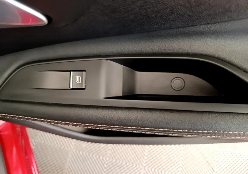 Détail de la commande de lève-vitre côté conducteur sur porte intérieure noire avec surpiqûres, Peugeot 3008 rouge 2021.