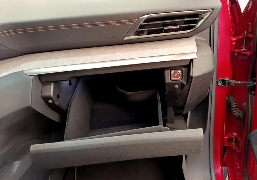 Vue intérieure côté passager du Peugeot 3008 rouge 2021, boîte à gants ouverte sous tableau de bord gris avec surpiqûres rouges.