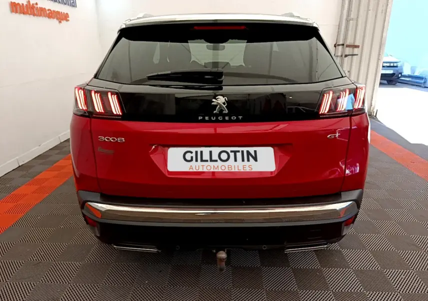 Vue arrière d’un Peugeot 3008 GT rouge avec feux LED caractéristiques et attelage visible en intérieur showroom.