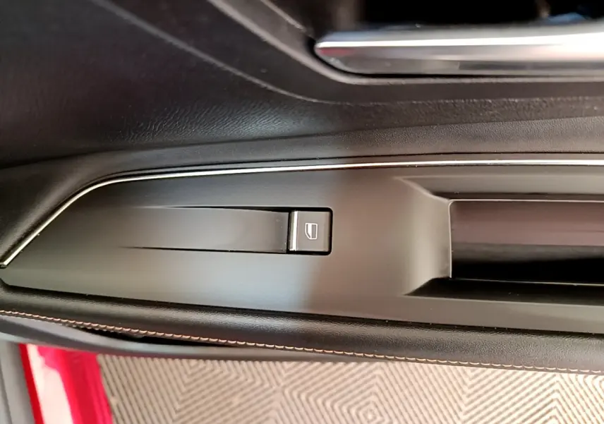 Détail de la commande de verrouillage des portes sur la portière côté gauche d’un Peugeot 3008 rouge.