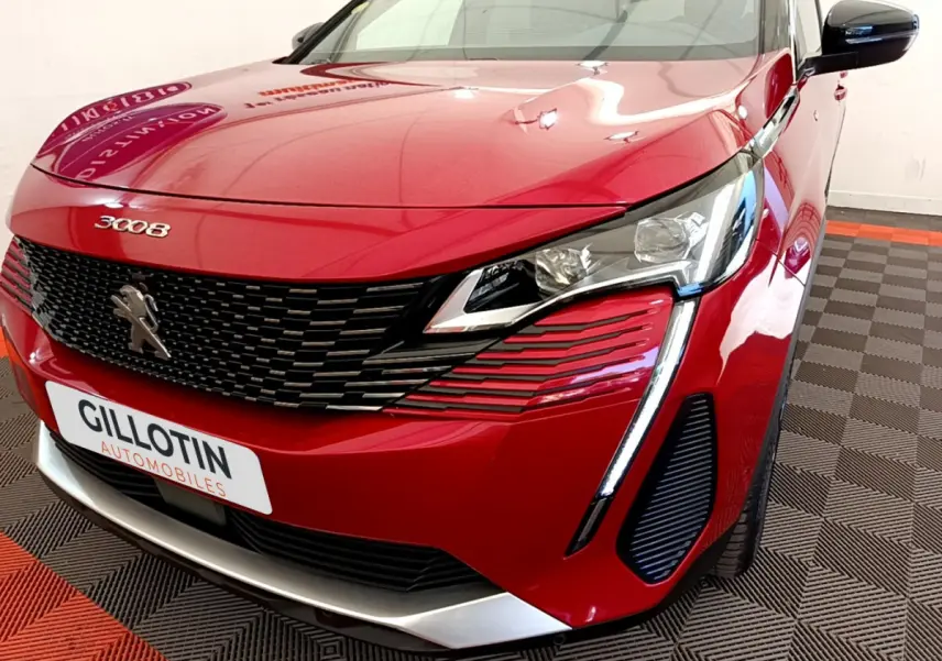 Vue avant droite rapprochée du Peugeot 3008 rouge avec calandre noire et feux LED distinctifs en forme de griffes.