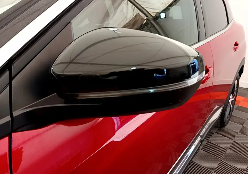 Gros plan sur le rétroviseur noir côté gauche du Peugeot 3008 rouge, avec partie latérale visible en arrière-plan.