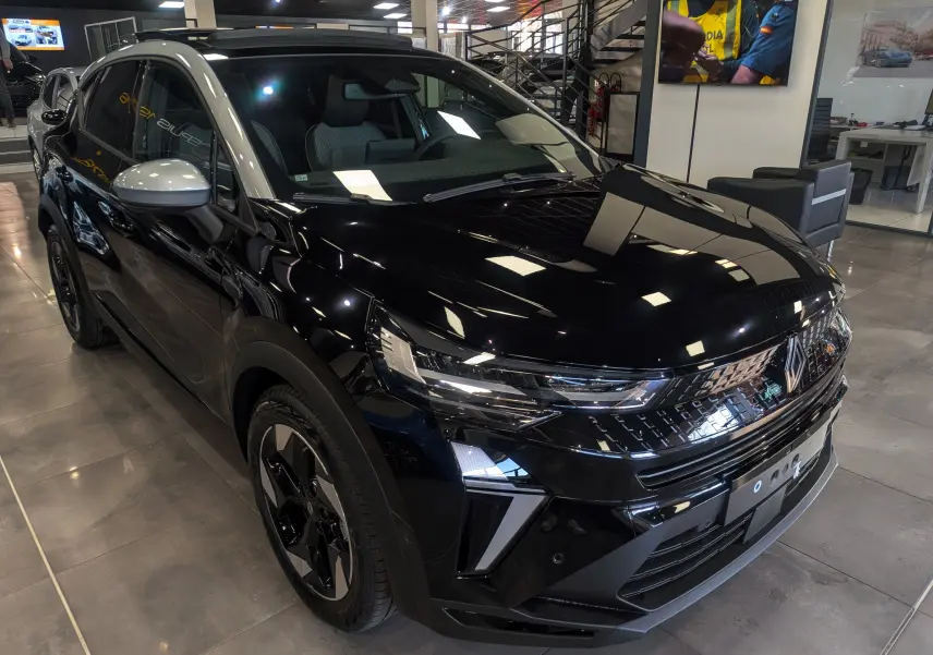 Renault Captur E-Tech hybride 2026 noir avec toit gris, vue 3/4 avant droit en intérieur showroom.