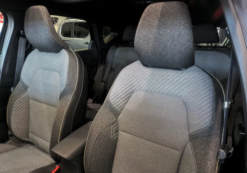 Vue intérieure sur les sièges avant tissu gris et noir du Renault Captur E-TECH 2026, avec accoudoir central visible.