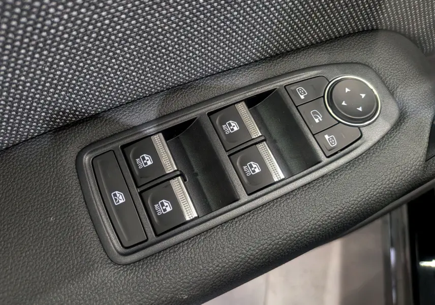 Panneau de commandes des vitres électriques et rétroviseurs sur la porte côté gauche d’un Renault Captur noir, intérieur tissu gris.