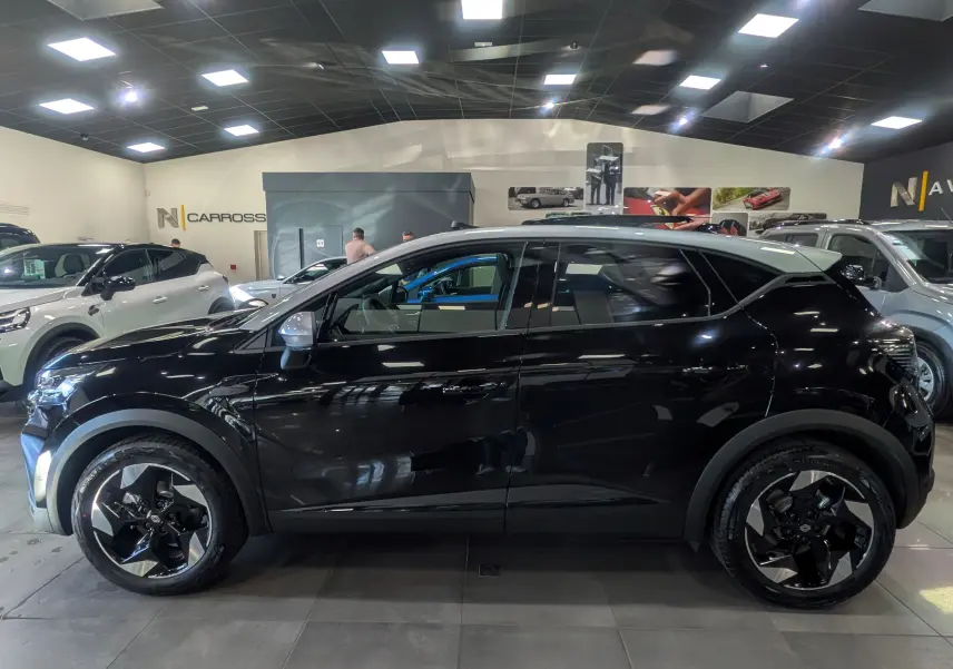 Renault Captur E-TECH 160 CH TECHNO noir avec toit gris Highland, vue profil côté gauche en intérieur showroom.