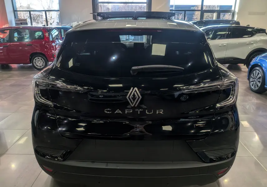 Vue arrière d’un Renault Captur E-TECH noir avec toit gris Highland, en intérieur de showroom.