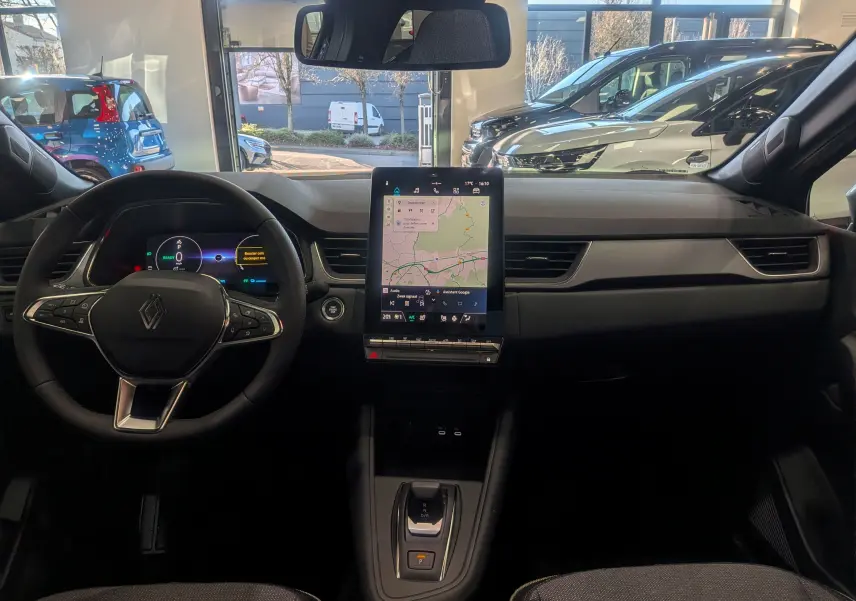 Vue intérieure frontale du tableau de bord du Renault Captur E-TECH avec écran tactile vertical et volant multifonction.