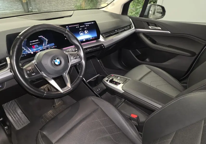 Intérieur noir de BMW Série 2 218d Active Tourer 2023, vue côté conducteur sur tableau de bord et volant cuir multifonctions.
