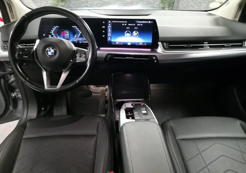 Intérieur BMW Série 2 218d gris, vue avant centrée sur tableau de bord numérique et console centrale moderne.