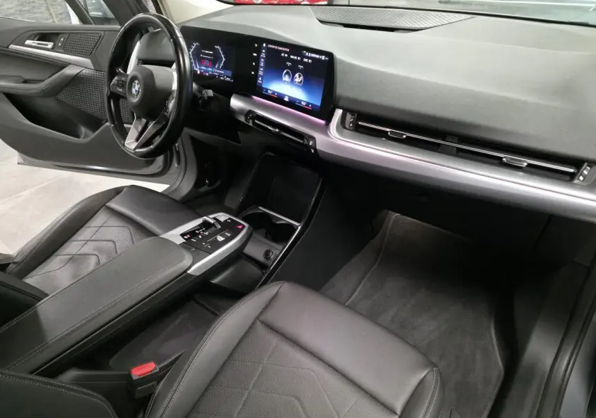 Intérieur avant de la BMW Série 2 218d gris, vue côté conducteur avec tableau de bord numérique et sellerie noire.