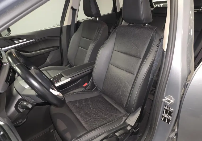 Vue intérieure côté conducteur de la BMW Série 2 218d gris, sièges en similicuir noir avec accoudoir central.