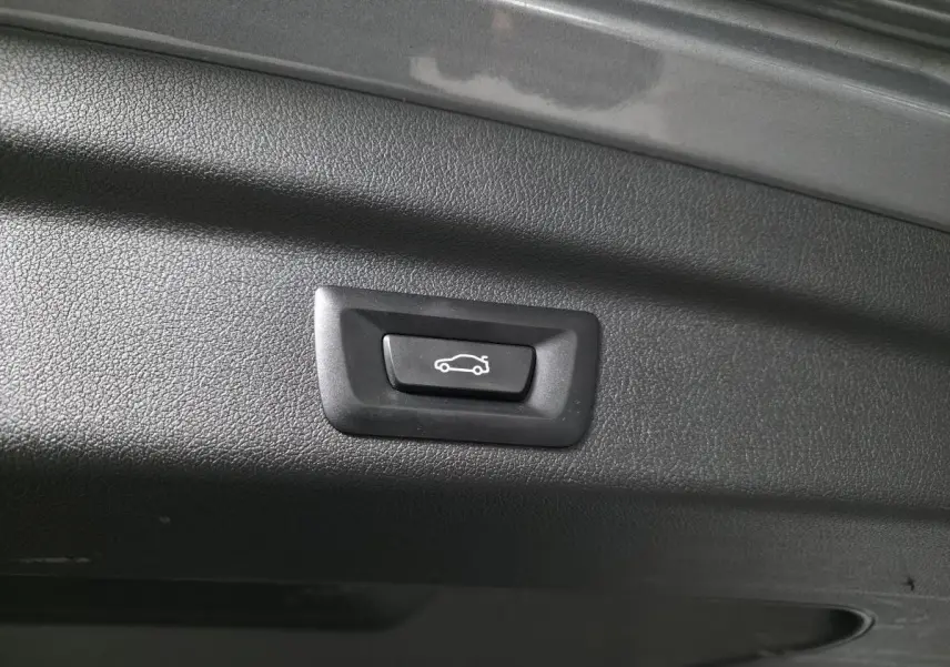 Bouton d'ouverture électrique du hayon sur la partie intérieure du coffre d'une BMW Série 2 gris métallisé.
