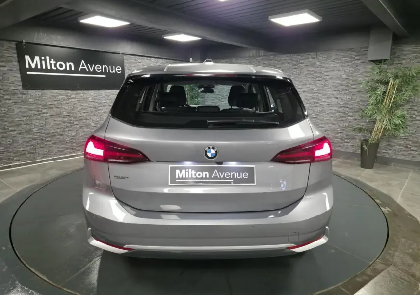 Vue arrière d'une BMW Série 2 Active Tourer gris métallisé avec feux LED allumés dans un showroom.